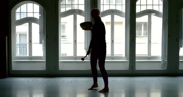 A Slender Girl Dances in a Trance with a Tibetan Bowl Singing in Her Hands