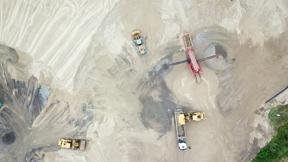 Excavator loader in sand quarry. View from above. Aerial view dumper trucks with cargo sand ridesing