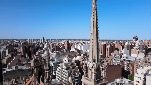 Aerial shot overlooking at high density downtown cityscape, pedestal down from tall spire reveals po