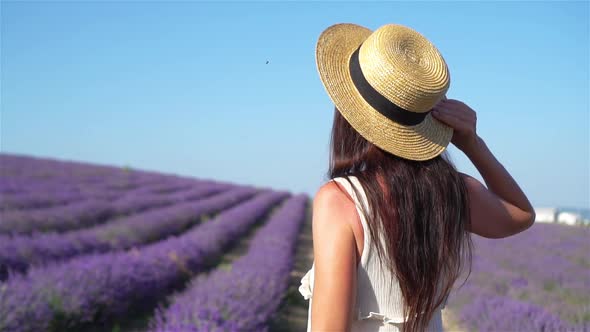 Woman in Lavender Flowers Field at Sunset in White Dress and Hat