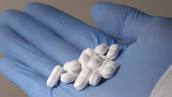 Closeup Shot of a Hand in Blue Rubber Gloves Holding Pills