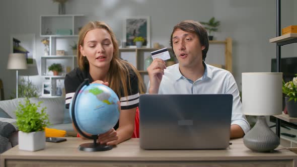 Young Beautiful Couple Chooses a Country on the Globe for Travel and Buys Tickets Online