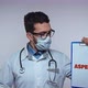 A Medical Professional Therapist Wearing a Stethoscope and Protective Face Mask Holds Up a Clipboard - VideoHive Item for Sale