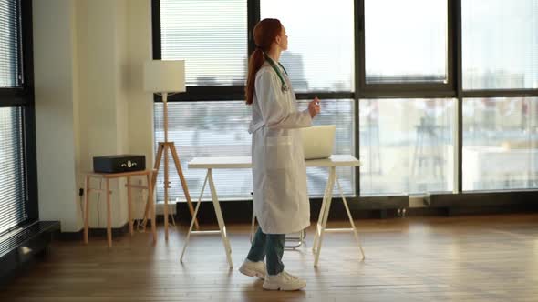 Happy Young Female Doctor Dancing Having Fun in Hospital Office Room of Medical Clinic on Background