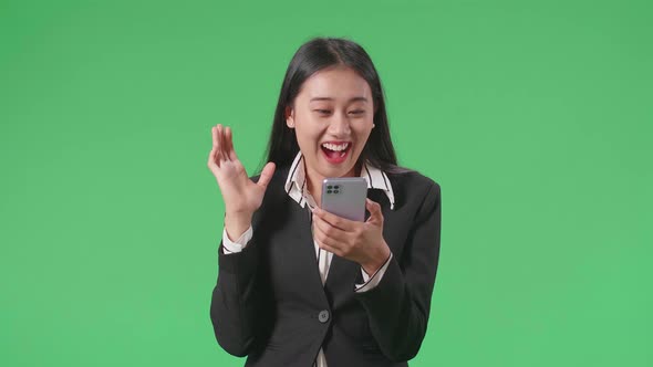 Business Woman Enjoy Using Mobile Phone And Say Wow While Standing On Green Screen In The Studio