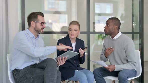 Young Business People Arguing While Holding Tablet Smartphone and Documents