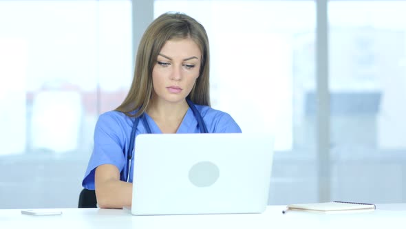 Young Female Doctor Typing on Laptop in Hospital