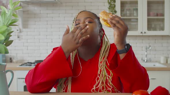 Obese African Female Eating Tasty Hamburger Indoor