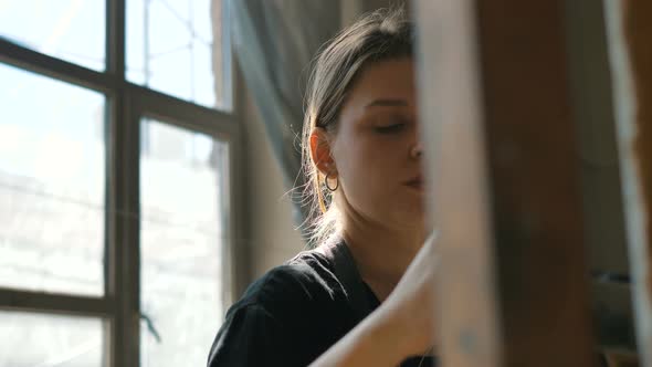 Female Artist Draws Picture with Brush in Sunny Art Studio