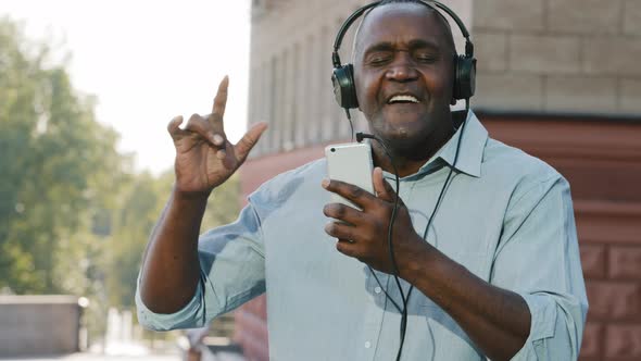 Funny Cheerful Emotional Senior African American Man Wearing Headphones Have Fun Moving Listening