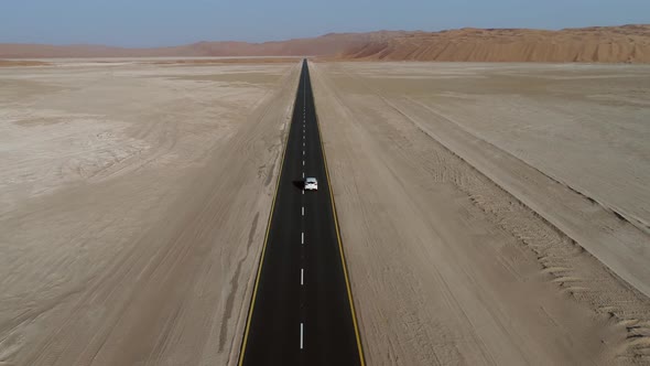 Aerial view of white car in clean road in the desert, Abu Dhabi, UAE.