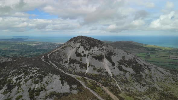 Approach and crest of mountain summit to bay view behind