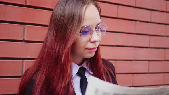 Young Woman Reading Newspaper on Street