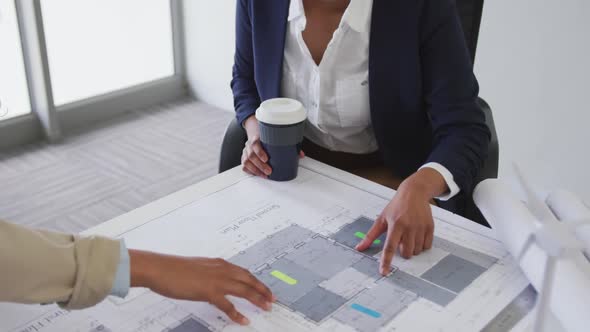 Biracial female architects talking and checking architects plans in modern office