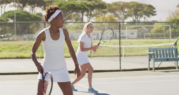 Video of happy diverse female tennis players exercising on court