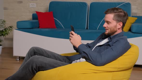 Young Man Playing Games on Phone, at Home.