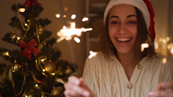 Slow Motion Extreme Close Up Face of Happy Laughing Woman in Santa Hat with Burning Sparklers in