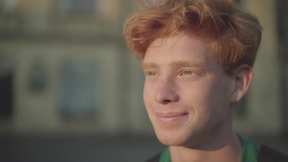 Close-up Portrait of Handsome Young Redhead Man in Sunlight. Smiling Caucasian Guy Enjoying Sunny