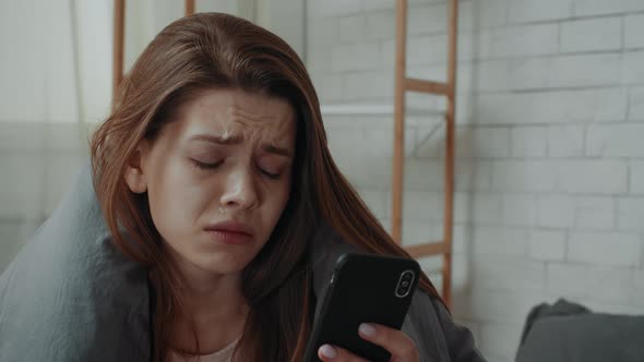 Desperate Young Lady Crying Looking At Cellphone In Bedroom Indoors
