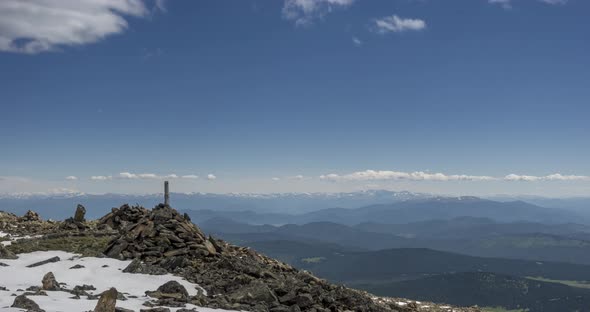 Time Lapse of Cloudscape Behind of the Mountains Top. Snow, Rocks, Cliffs and Deep Blue Sky