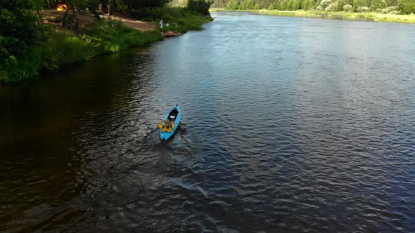 Aerial Back View of a Man in a Yellow Jacket Floating in a Kayak