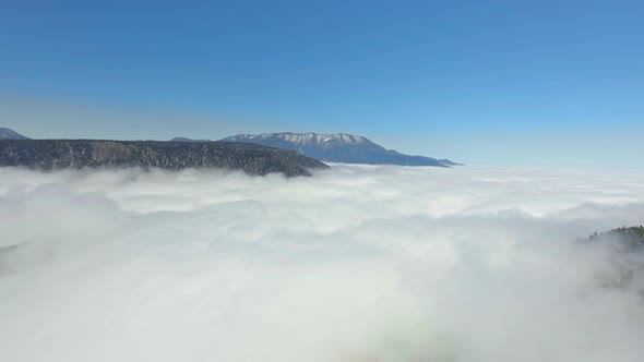 Bird's-eye drone view over a thick layer of clouds that enveloped the earth in California, USA