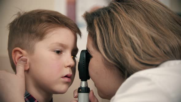 Boy Having a Treatment in Eye Clinic - a Woman Doctor Checking Little Boy's Eye Vision By Using a