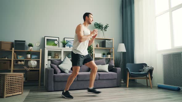 Handsome Young Guy Exercising at Home Doing Sports Exercises for Legs and Body