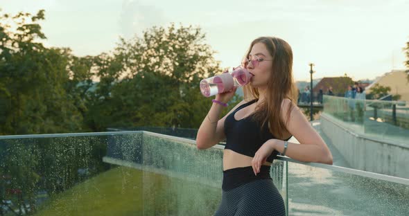 The Sport Girl is Leaning Against the Glass Railing