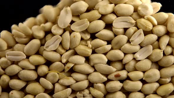 Falling blanched peanuts on a black background.