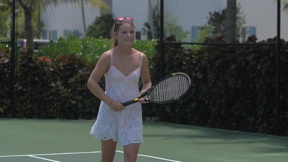 A young woman playing tennis with her boyfriend while on vacation.