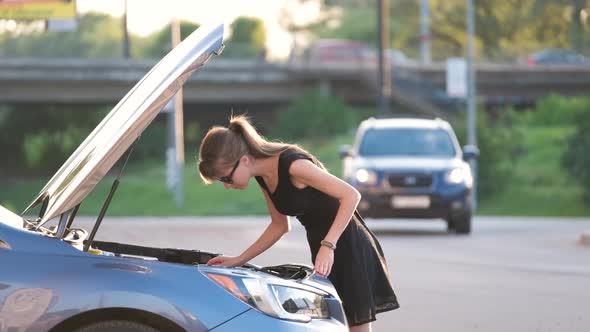 Helpless Woman Standing Near Her Car with Open Bonnet Inspecting Broken Motor