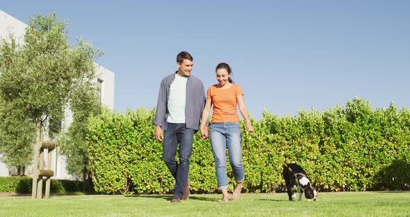 Happy caucasian couple is taking their dog for a walk