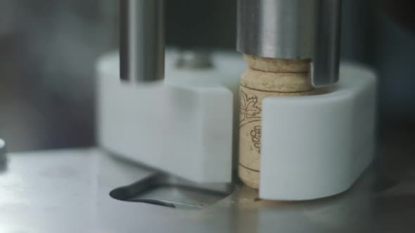 Wine cork is inserted into the bottle on a machine. Close-up