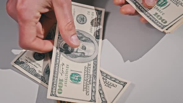 Male Hands Counting Old Hundred Dollar Banknotes on a White Table