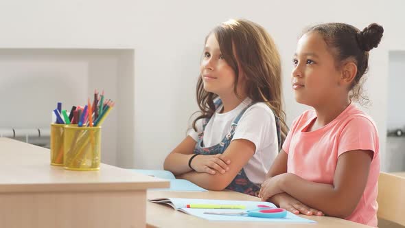 Two Schoolgirls Sit a Desk in Classroom and Listen Carefully To the Teacher