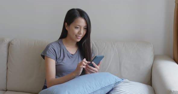 Woman use of mobile phone and sit on sofa at home