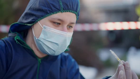 Closeup Portrait of Female Criminalist in Uniform Face Mask and Gloves Examining Poison in Ampoule