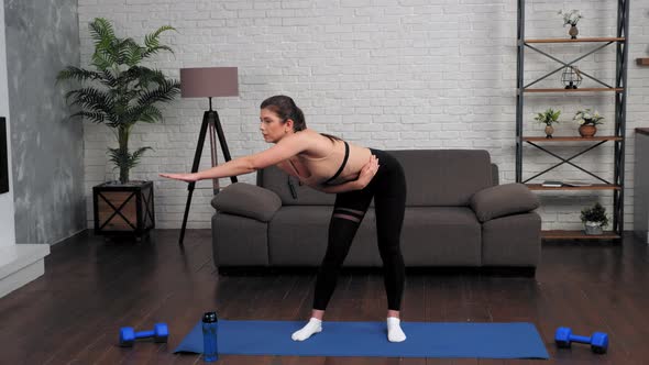 Young Fit Woman in Sportswear Doing Warmup Before Workout on Yoga Mat at Home