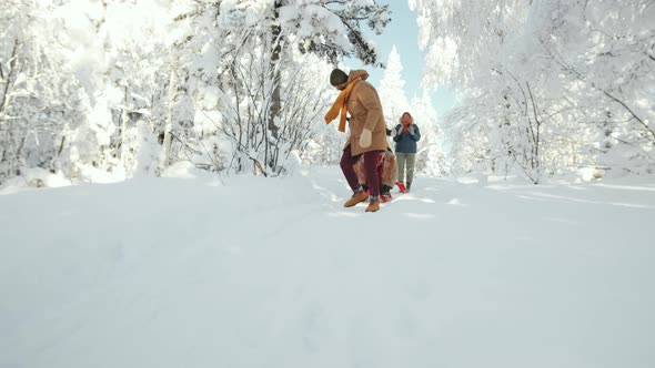 Male Friends Riding Sled and Having Fun in Forest on Winter Day