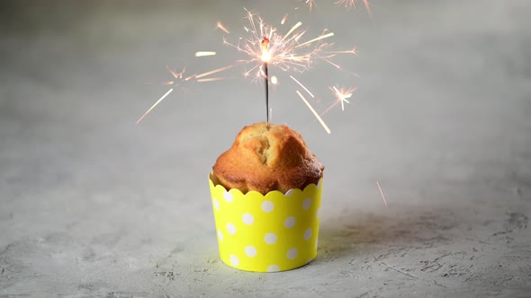 Valentines day cupcake or muffin with sparklers in a yellow form on a gray background