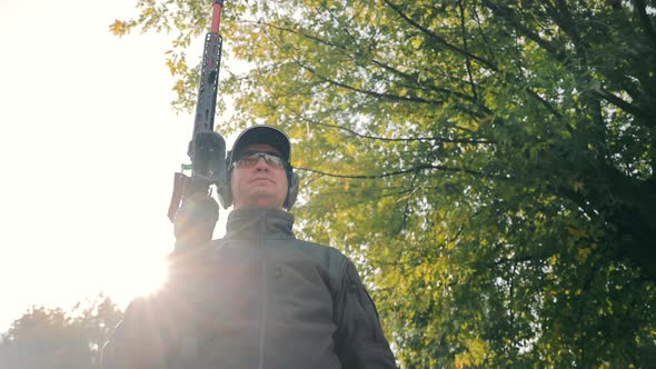 Portrait of a Male Hunter with a Smoothbore Hunting Weapon in His Hands on Headphones and Goggles