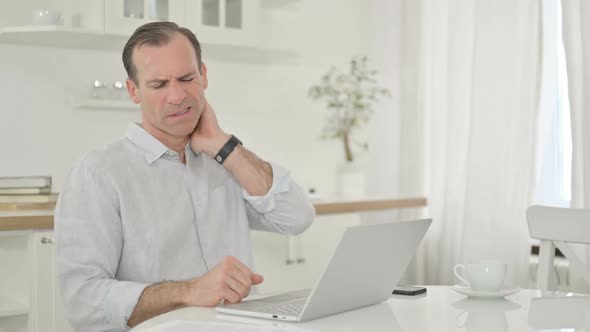 Middle Aged Man with Laptop Having Neck Pain at Home