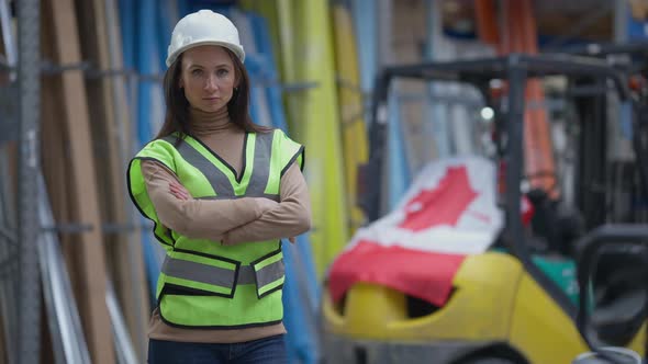 Serious Woman Crossing Hands Looking at Camera with Canadian Flag on Forklift at Background