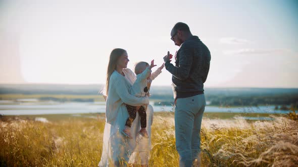 Young Happy Family with Little Baby Standing on the Field