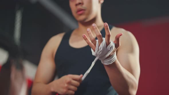 Active handsome athlete man removing exercise wrapping glove in hand for workout at fitness gym.