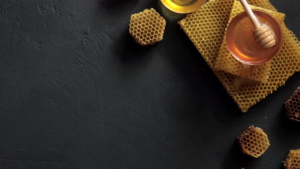 Honey dipper on the bee honeycomb on black table. Horizontal composition 4K UHD video footage