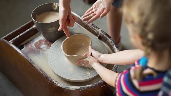 Little Girl Giving Heart Shape To a Clay Bowl