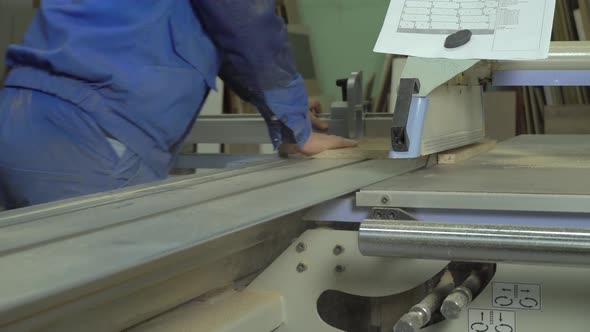 A man cuts a wooden slab on a format cutting machine