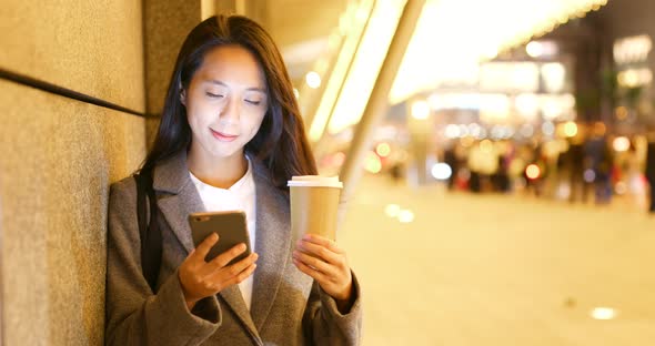 Asian businesswoman use of mobile phone and hold with hot coffee